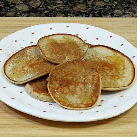Foto de las tortitas amontonadas sobre un plato pequeño, y una tabla de madera de fondo