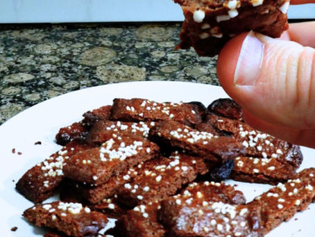 Foto de un plato lleno de galletas, y una mano mostrando una galleta partida por la mitad