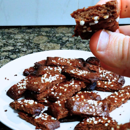 Foto de un plato lleno de galletas, y una mano mostrando una galleta partida por la mitad
