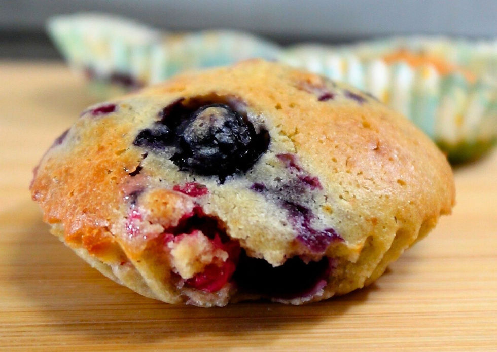 Foto cercana de un muffin, en el que se ve un arándano grande en primer plano