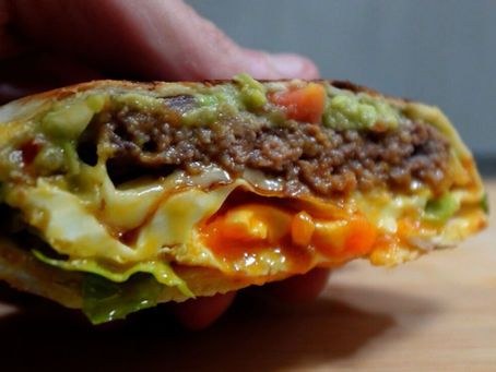 Foto detalle del wrap visto desde delante, se ve (de arriba a abajo) la capa de guacamole, carne picada, queso, huevo y lechuga