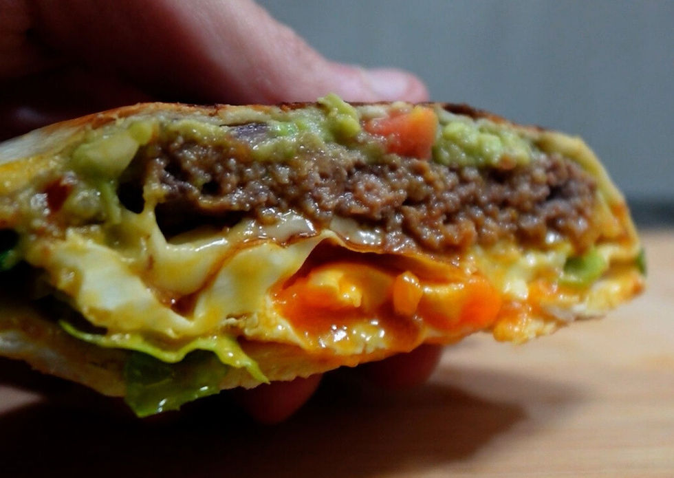 Foto detalle del wrap visto desde delante, se ve (de arriba a abajo) la capa de guacamole, carne picada, queso, huevo y lechuga