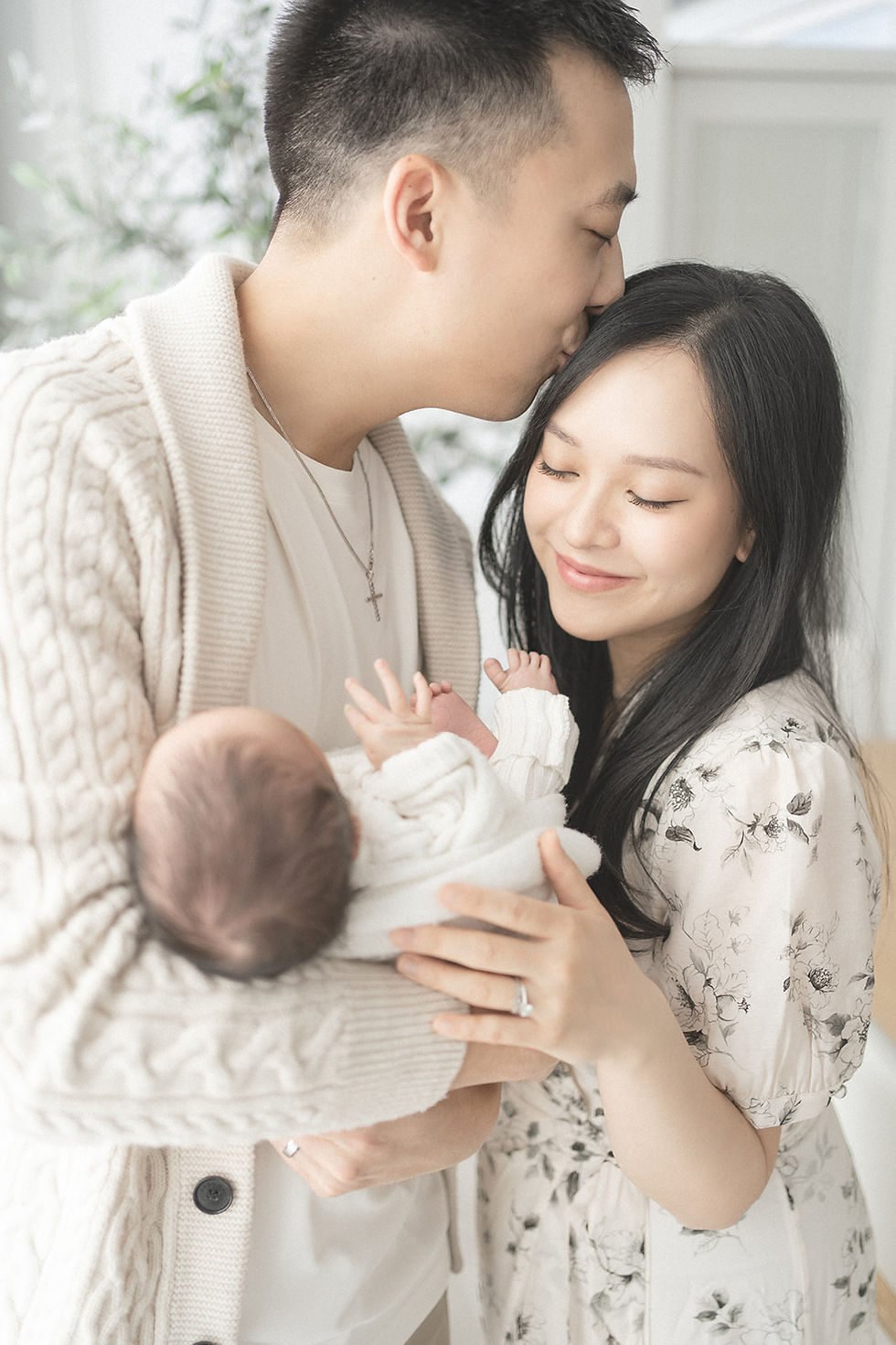 A man kisses his wifes head while they both hold their new baby in Edmonton.