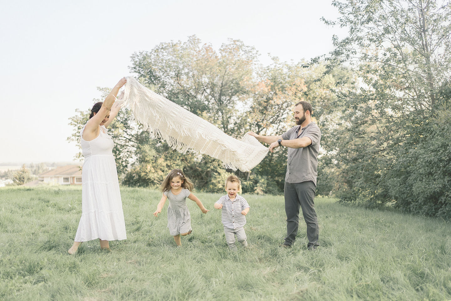 A family plays with their two little children at their photoshoot in Beaumont, Alberta.