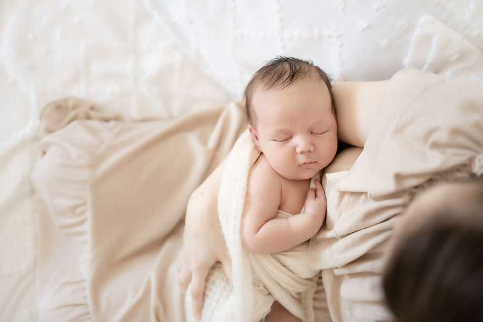 A baby sleeps while being held by his Mother at his Newborn Photography Session.