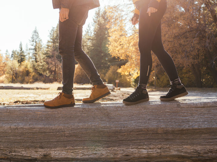Couple walking along a fallen tree with new Forsake shoes with Fall leaves in background