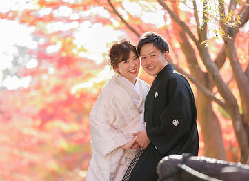 名古屋の東山植物園で新郎新婦が紅葉を背景に、笑顔で寄り添い合う様子を捉えた和装前撮り＆フォトウェディングのシーン。