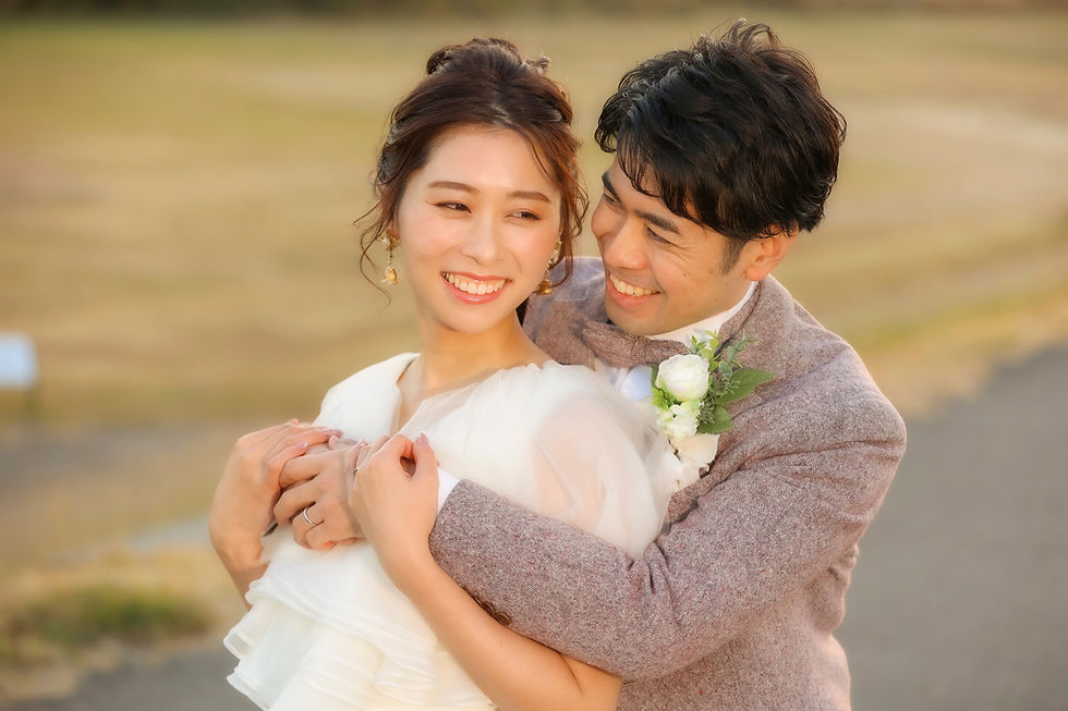名古屋の前撮りで、夕日の中で新婦を優しく抱きしめる新郎が見せる、温かな笑顔のウェディングフォトのワンシーン