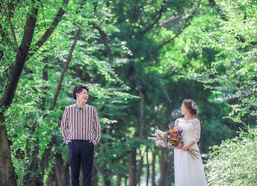 名古屋で前撮りを行なった新郎と新婦。緑豊かな自然の中、新緑が太陽の光に照らされて輝くロケーションで、互いを愛情深くにこやかに見つめるシーンを捉えたウェディングフォト。