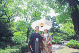 名古屋の鶴々亭での緑溢れる庭園を背景に和傘をさす和装カップル、木漏れ日の中でのロマンチックな前撮りシーン