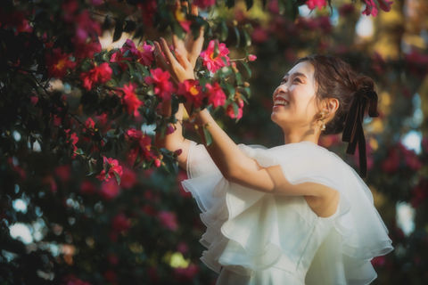 名古屋の庭園でピンクの花々に囲まれ、楽しそうに手を伸ばす新婦、フォトウェディングの一コマ