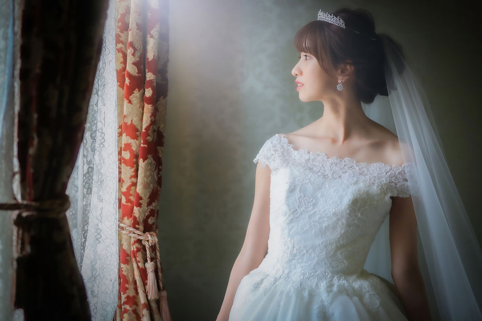名古屋での前撮りシーン、優雅なレースのウェディングドレスとティアラを身につけた新婦が窓辺で思いにふけるシーン