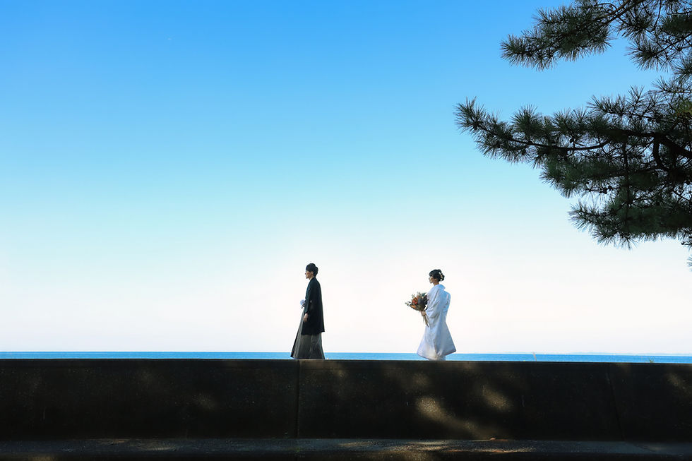 青空を背景に堤防を和装姿で歩く新郎と新婦を撮影した前撮り写真