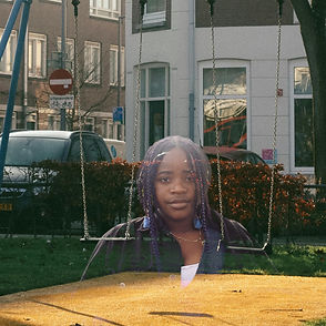 The photo of a young woman of colour is superimposed over a photo of some swings in a public garden