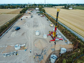 Übersicht einer Tiefbaustelle mit Kran beim Einbau von Betonschächten und Infrastrukturkomponenten