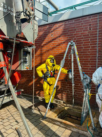 Mitarbeiter in Schutzanzügen bei Arbeiten an einer Kanalsanierungsanlage