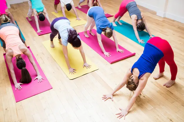 trainer-assisting-group-people-with-downward-dog-yoga-exercis_1170-170