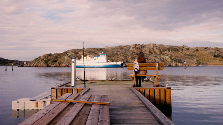 Personne assise sur un banc au bout d'un quai près d'un bateau.
