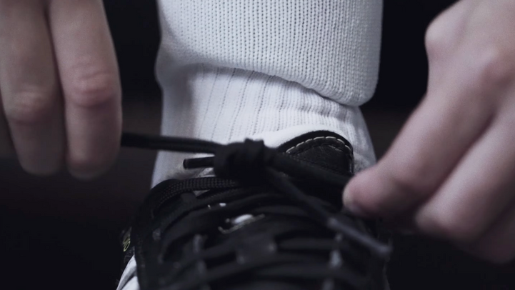 Une personne noue les lacets de ses chaussures de sport noires.