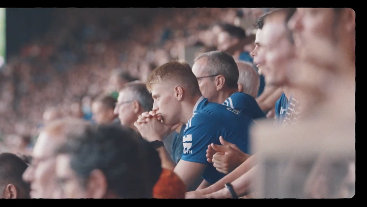 Spectateurs attentifs regardant un match de football depuis les tribunes.