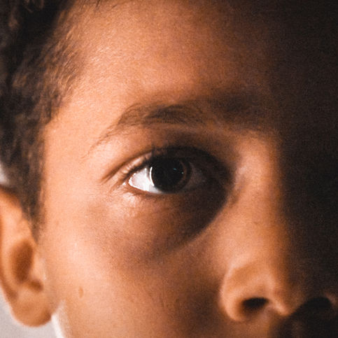 Visage d'enfant, un œil illuminé, l'autre dans l'obscurité.