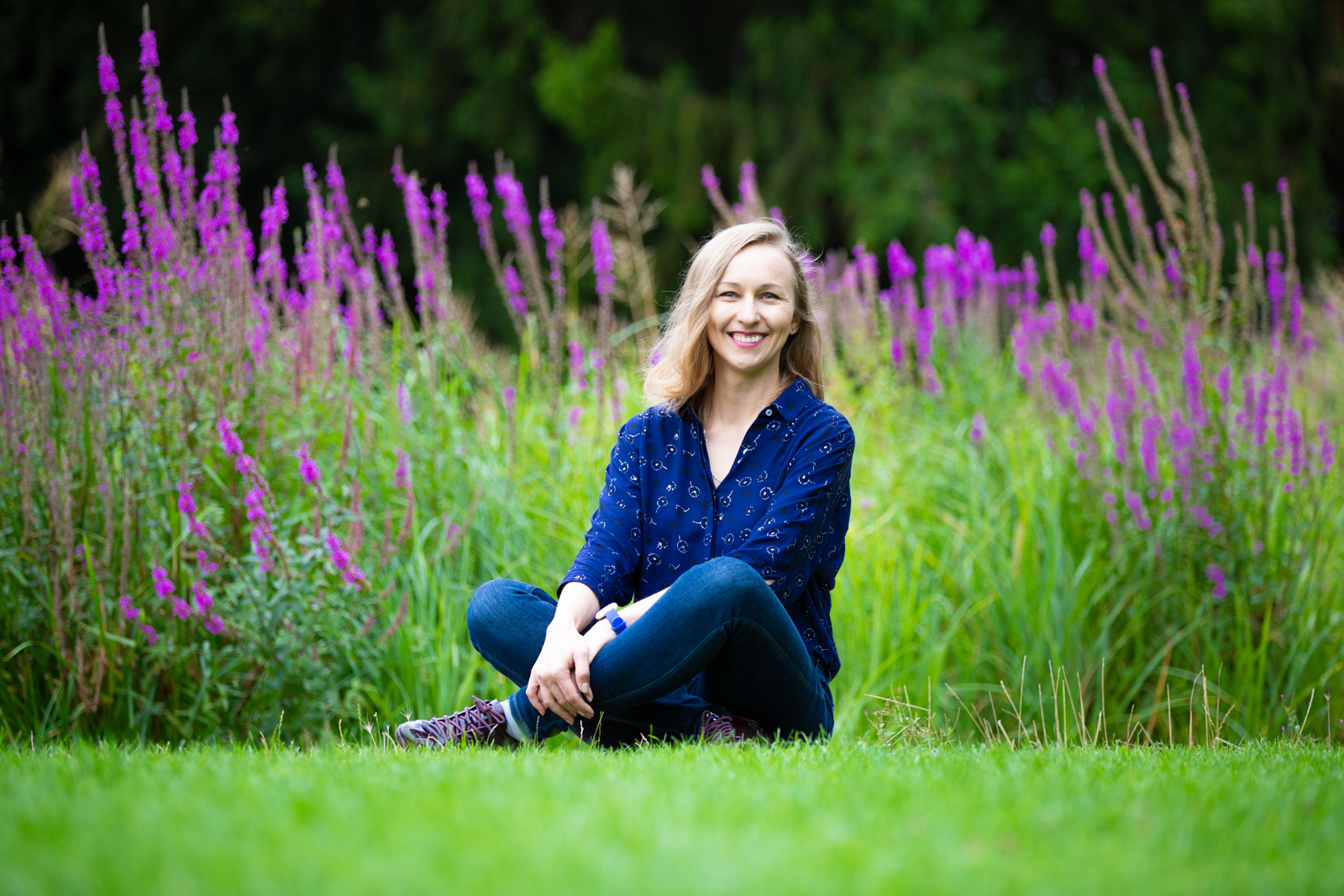Anna Wolas sitting on the grass in front of purple flowers