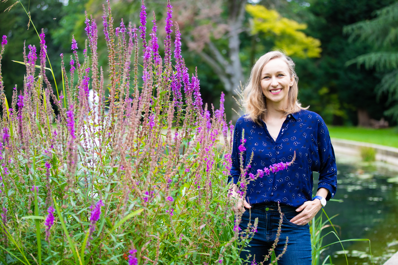 Anna Wolas, career wellbeing coach, smiling beside purple flowers in a garden