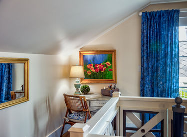 Desk with rattan chair, colorful painting, blue curtains