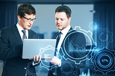 two-attractive-young-european-businessmen-with-laptop-glowing-cogwheel-chart-hologram-blur