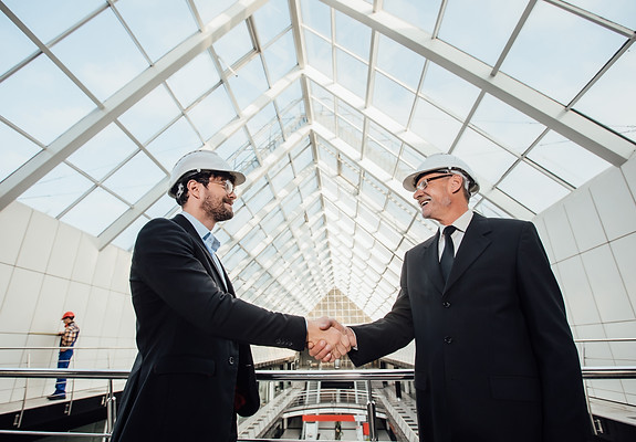 two-cheerful-businessman-handshaking-helmet-new-building.jpg