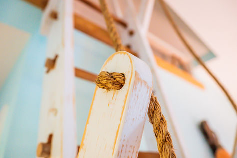 Rope knotted through white wooden ladder
