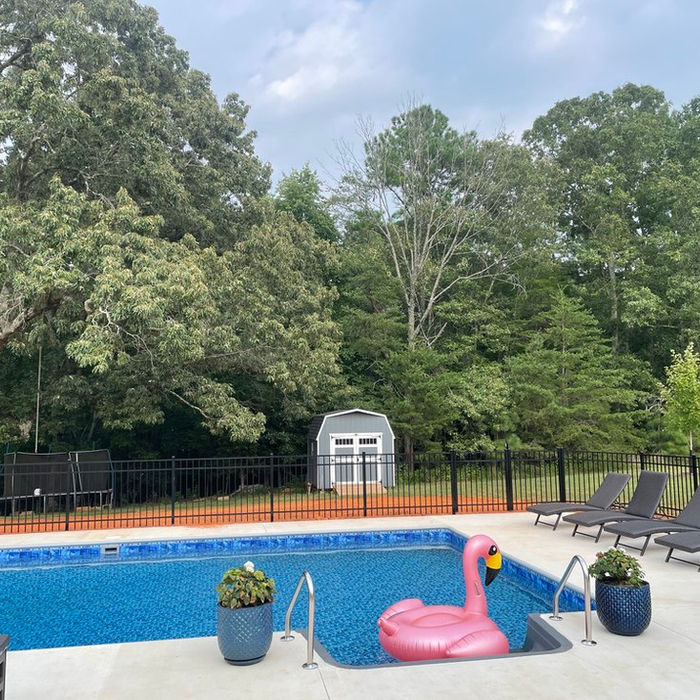 Outdoor swimming pool with pink flamingo float and lounge chairs