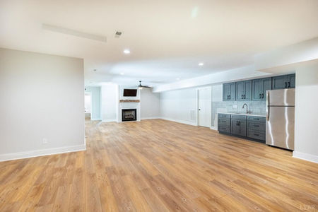 Open room with wood floor, fireplace, and kitchenette