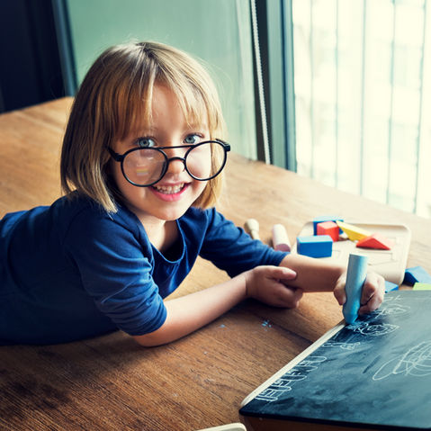 young-caucasian-girl-lying-floor-drawing-chalk-board.jpg