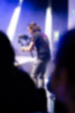 Ein Kameramann von FRB Media aus Wien produziert dynamische Eventaufnahmen während einer Bühnenperformance, spezialisiert auf Event- und Messefotografie.