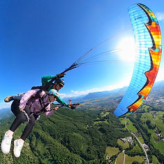 Tandem paraglider in a thrilling spiral maneuver high above Salzburg's lush green landscape.