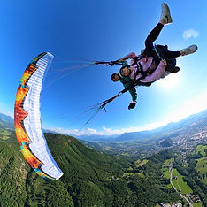 Tandem paraglider performing a thrilling maneuver high above Salzburg, with city and Alpine panorama below