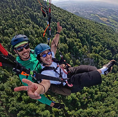 Tandem paraglider flying above Gaisberg's lush green forest, with panoramic views of the Austrian valleys
