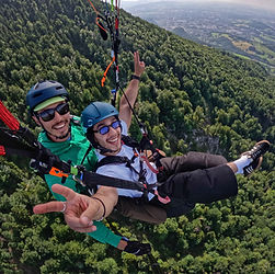 Tandem paraglider flying above Gaisberg's lush green forest, with panoramic views of the Austrian valleys