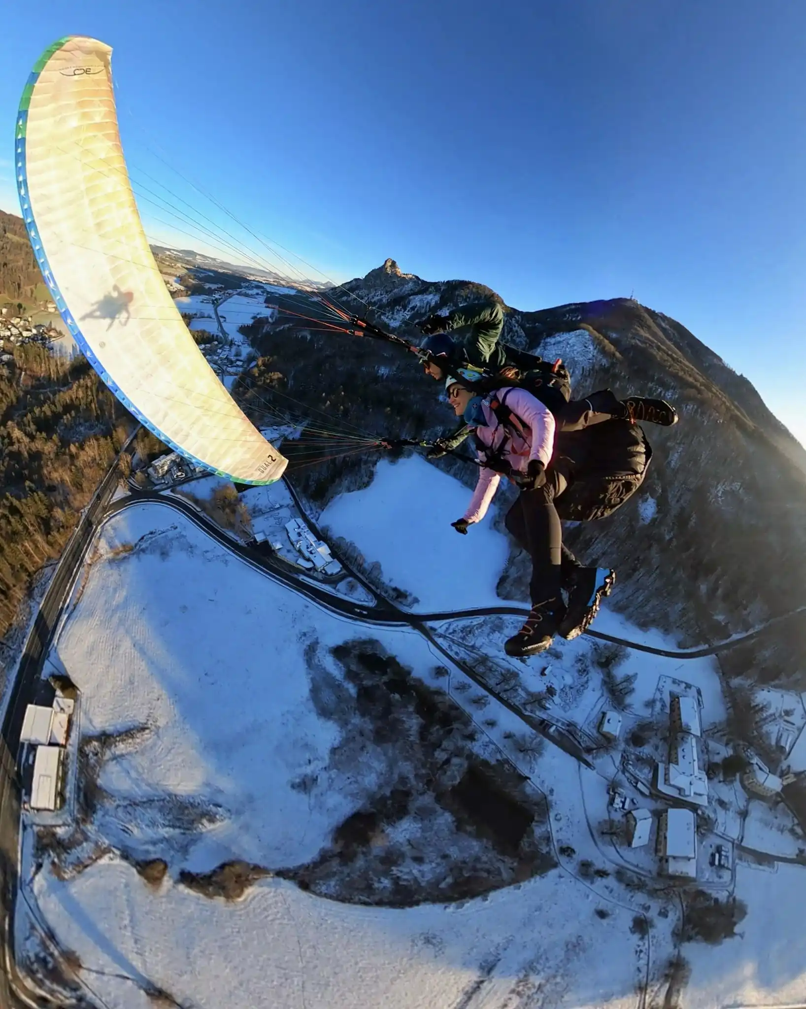 Tandem Paragliding doing exciting manouevers over snowy landing area in Guggenthal, Salzburg
