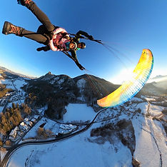 Tandem paragliding Top-Action flight over snowy Salzburg Alps.
