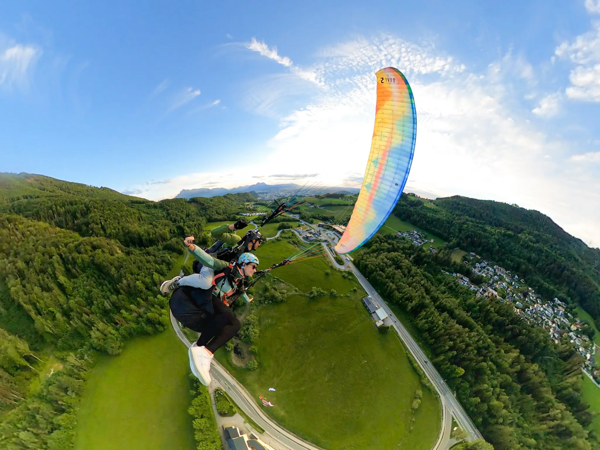 Tandem paragliding over the lush landing area in Guggenthal, Salzburg, performing thrilling manoeuvres.