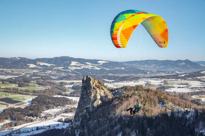 Winter-Paragleiten: Tandemflug über dem schneebedeckten Guggenthal, mit Blick auf den Nockstein