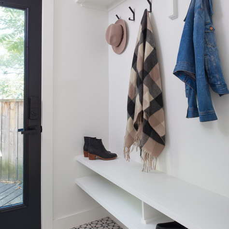 White mudroom bench with black and white patterned tile floor
