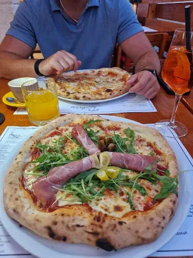 Neapolitan pizza with prosciutto and arugula at Tudors restaurant in Split, served outdoors.