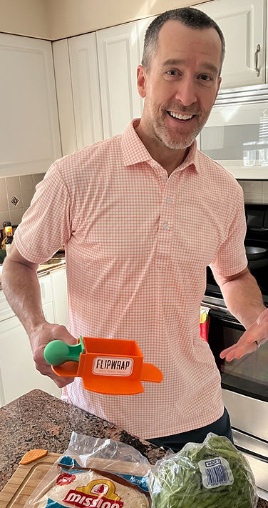 Eric Teasdale, founder of The FLIPWRAP Company. He's a white man posing next to the prototype of FLIPWRAP which consists of a device and the tamper