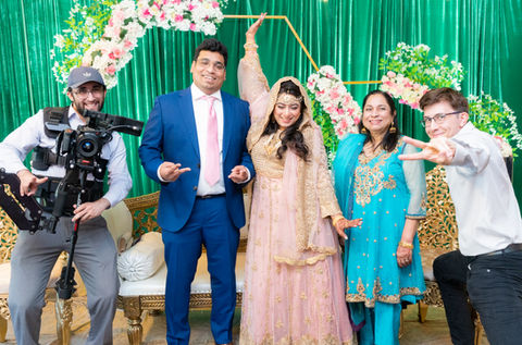 Couple on wedding outfits posing while smiling next to Arazo crew