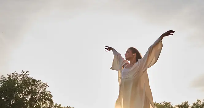 a-woman-in-white-clothing-stretches-her-arms-wide-2024-07-12-21-46-47-utc-scaled.webp