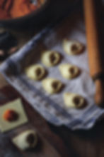 freshly made pumpkin tortelli drying on a towel with a bowl of pumpkin filling and rolling pin