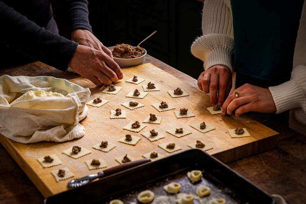 a couple making pasta together on a wooden bench